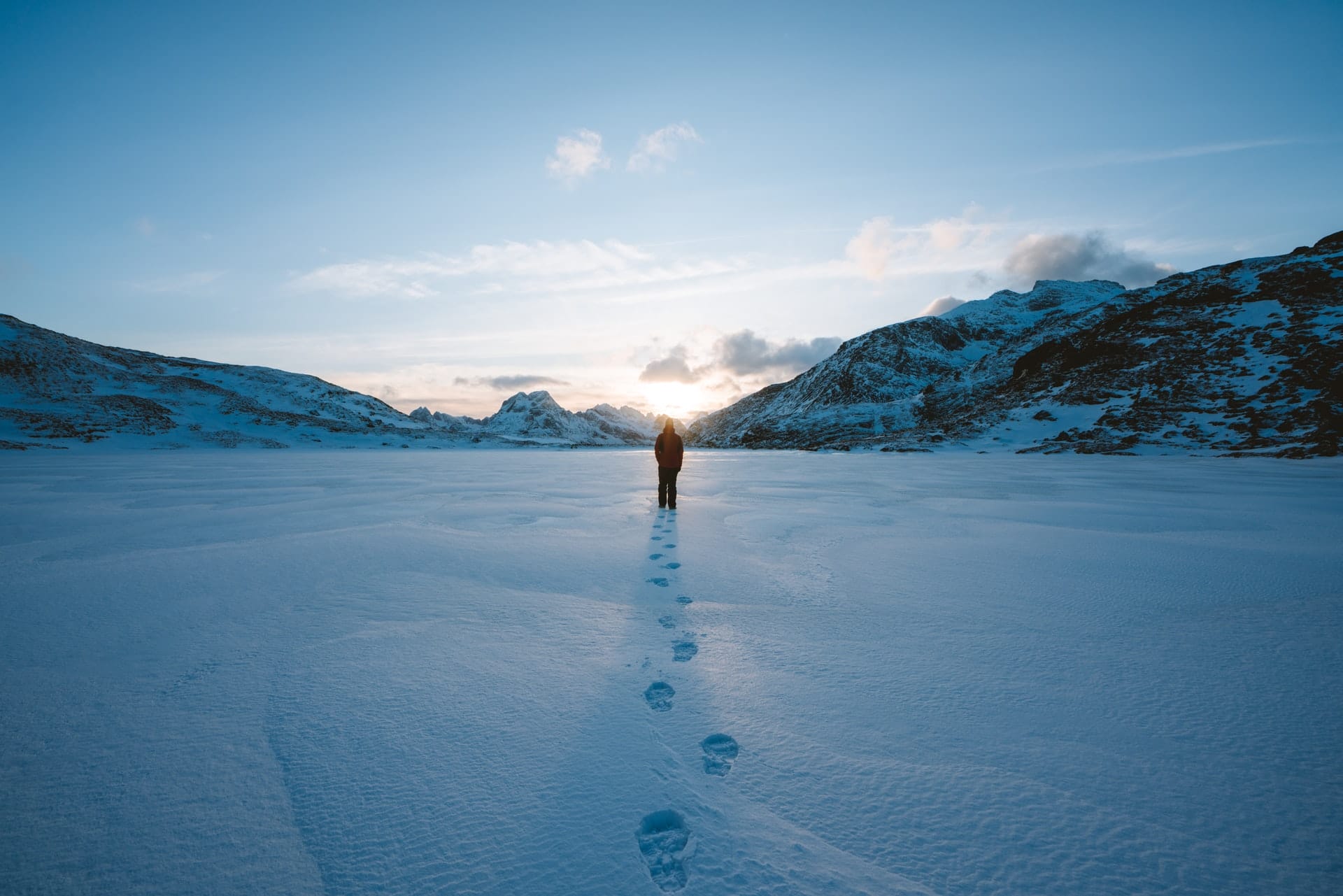 Person walking through snow with mountains in the distance.