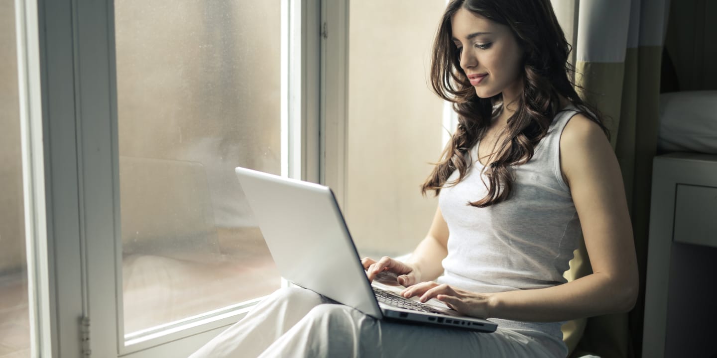 Woman sitting by window using laptop.