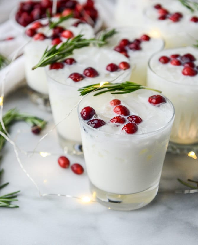 White drink with ice, rosemary and cranberries in it.