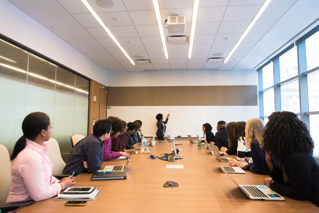 A group of people listing intuitively to a presenter at a board meeting.