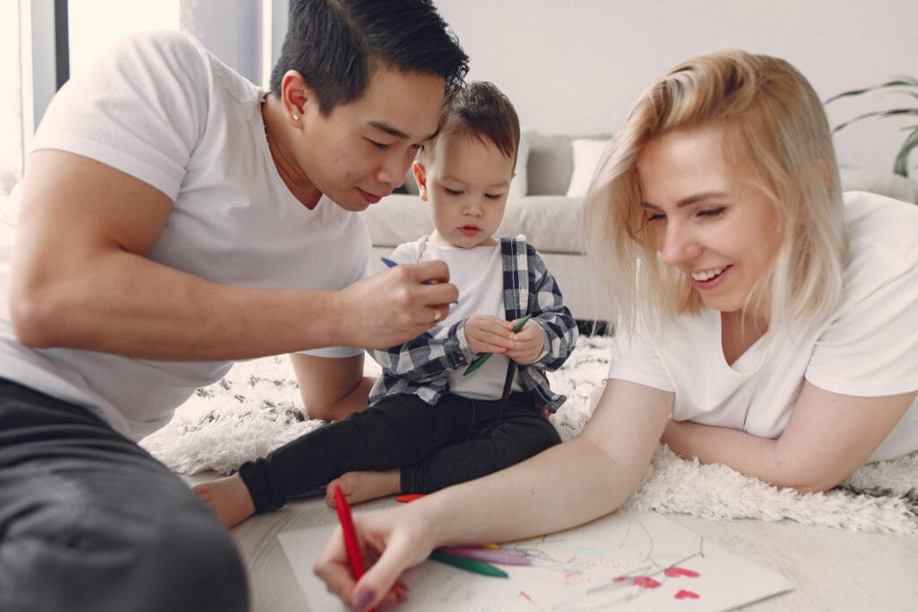 Family of three laying on floor colouring.