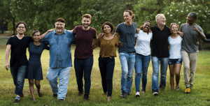 Diverse group of people walking arm in arm on grass.