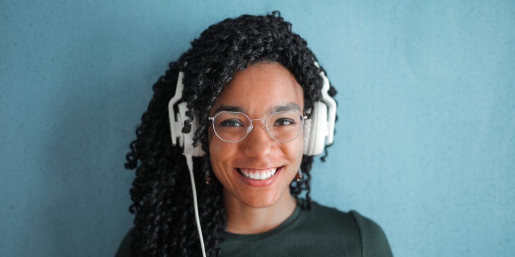 Cheerful woman wearing glasses and headphones smiling for photo.