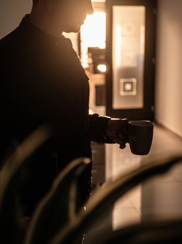 Man standing and holding coffee mug.