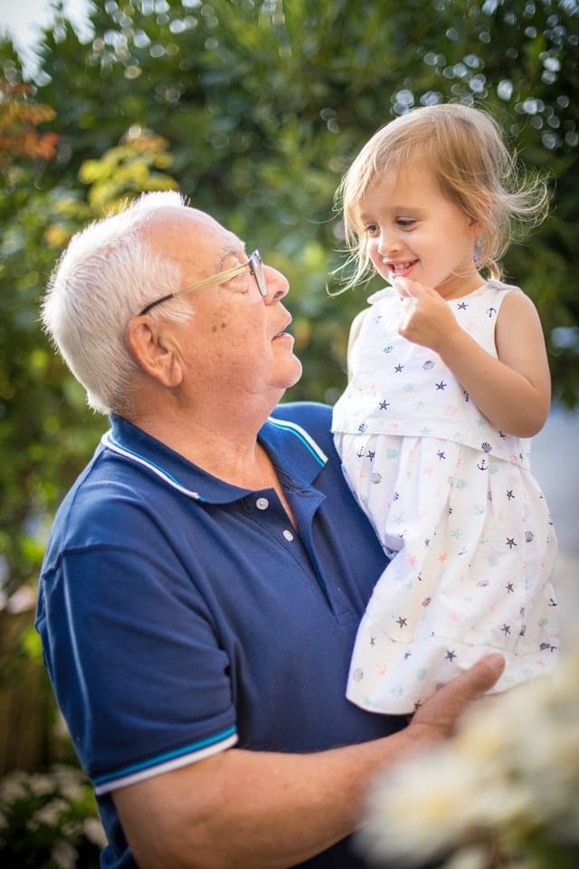 Older man sitting and holding a child.